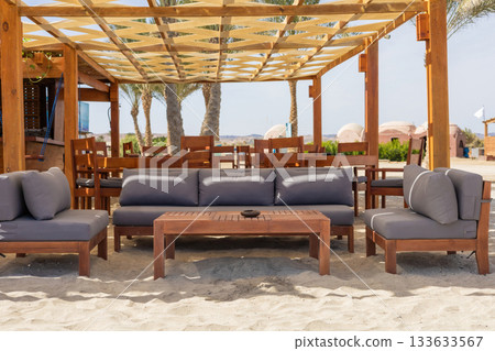 Outdoor lounge area with wooden furniture on a sunny beach setting 133633567