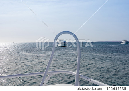 Tranquil ocean voyage with distant yachts under clear sky 133633586