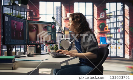 Woman expert developer works with photo editing software in the creative workspace, digital media. Using dual monitors to ensure productivity and innovation in the graphic design world. Camera A. 133633791