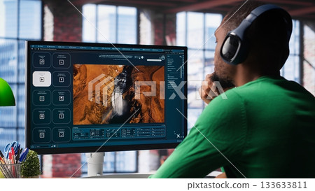Computer screen displays digital visuals generated through AI. Young person uses software combining data and machine learning, text prompts to design graphics at home office. Camera A. 133633811