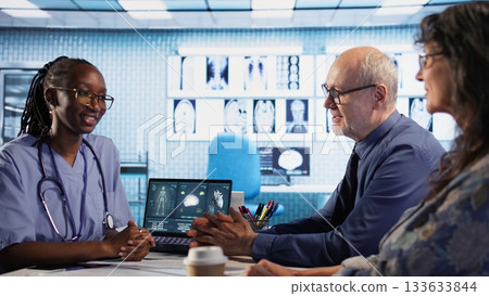 African american assistant and patients engage in medical checkup with hospital records and x ray results files to find accurate treatment for wellness and recovery. Healthcare practices. Camera A. 133633844