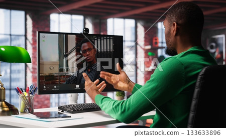 Male worker calls manager remotely using internet video call to ask for feedback on project progress. Teleworker requesting assistance from team leader in teleconference meeting. Camera A. Male worker calls manager remotely using internet video call to ask for feedback on project progress. Teleworker requesting assistance from team leader in teleconference meeting. Camera A. 133633896