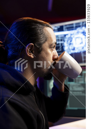 Hacker in secret lair drinking coffee, using AI to break into secure computer systems and bypass security. Man enjoying beverage, using deep learning to attack weak spots in company networks Hacker in secret lair drinking coffee, using AI to break into secure computer systems and bypass security. Man enjoying beverage, using deep learning to attack weak spots in company networks 133633929
