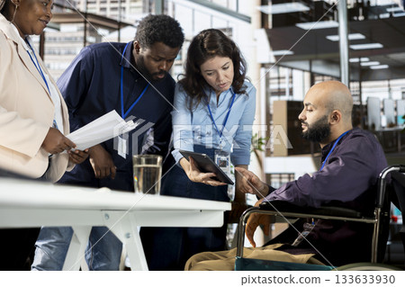 Multiethnic employees team sharing ideas and details for achieving goals, discussing about data analytics and reports. Middle eastern man meeting with colleagues in disability friendly space. Multiethnic employees team sharing ideas and details for achieving goals, discussing about data analytics and reports. Middle eastern man meeting with colleagues in disability friendly space. 133633930