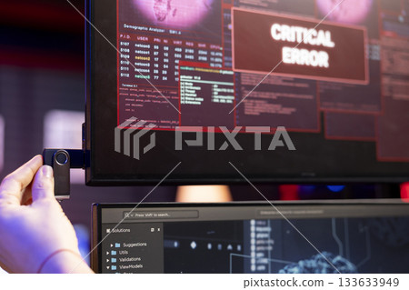 Close up of hacker using USB stick to do data breach, getting interrupted by critical error alert. Cybercriminal plugs in USB driver, trying to run AI malware, getting blocked by security systems 133633949