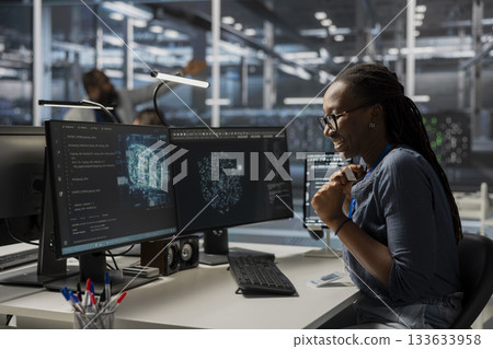 Happy engineer in data center using AI powered tech to run simulations. Cheerful employee coding cognitive computing algorithms to extract insights from data and automate rigs 133633958