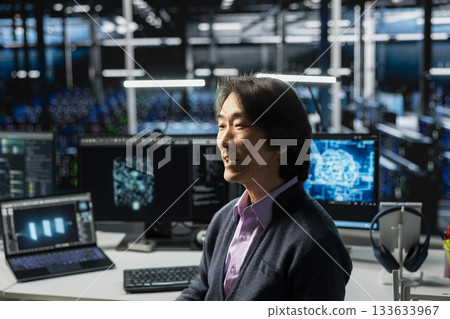 System administrator in data center using PC, managing AI training datasets. Asian man using computer program to oversee machine learning in server room supporting scalable infrastructure for AI apps System administrator in data center using PC, managing AI training datasets. Asian man using computer program to oversee machine learning in server room supporting scalable infrastructure for AI apps 133633967
