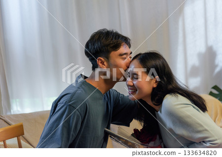 Young couple happy in love man kisses woman at home romantic valentine day moment showing deep affection celebrating connection sweet gesture creates joyful memory for perfect for anniversaries. Young couple happy in love man kisses woman at home romantic valentine day moment showing deep affection celebrating connection sweet gesture creates joyful memory for perfect for anniversaries. 133634820