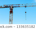 Close-up Red-and-white Tower Crane on Construction Site against Blue sky on Sunny day. Column Crane Boom arrangement with Hook suspension and Counterweight at Ends. 133635182
