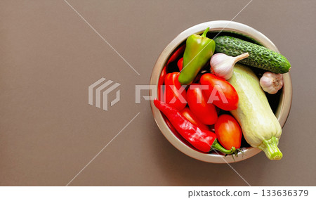 Composition of fresh vegetables in a bowl on a gray background, top view with space for text 133636379