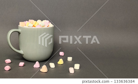 A gray cup with a marshmallow heart on a gray background. Space for text. 133636384