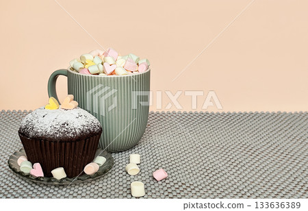 Chocolate cupcake and cup with marshmallows on beige gray background. Chocolate cupcake and cup with marshmallows on beige gray background. 133636389