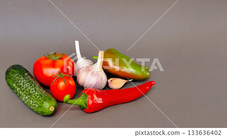 Composition of tomato, cucumber, feather and garlic on gray background, top view with space for text Composition of tomato, cucumber, feather and garlic on gray background, top view with space for text 133636402