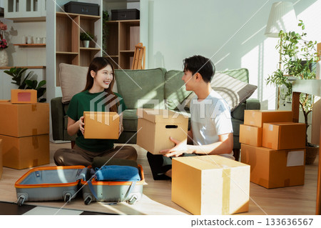 young couple helps put things in boxes and prepares to move to a new house. young couple helps put things in boxes and prepares to move to a new house. 133636567