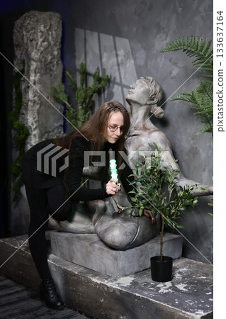 Woman carefully arranging greenery around statue during sunset ambiance Woman carefully arranging greenery around statue during sunset ambiance 133637164