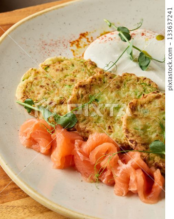 delectable smoked salmon and zucchini pancakes, gourmet plate featuring seafood and fresh vegetables 133637241