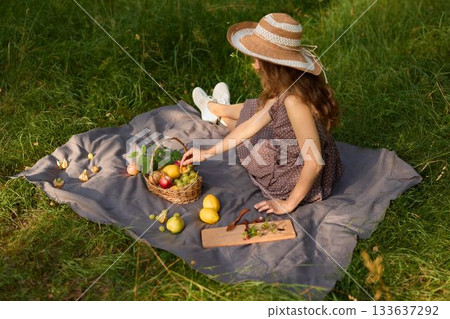 caucasian child forager arranging fruit basket in meadow 133637292