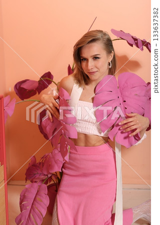 Happy student holding huge vibrant pink plant with bright smile 133637382