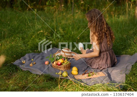 Peaceful scene depicting woman resting on blanket amid nature and sunlight Peaceful scene depicting woman resting on blanket amid nature and sunlight 133637404