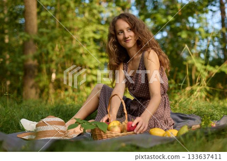 Young woman enjoying laidback picnic with fresh fruit and bread Young woman enjoying laidback picnic with fresh fruit and bread 133637411