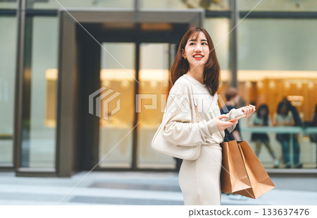 Single adult asian woman holding smartphone and shopping bag on black friday sale city lifestyle Single adult asian woman holding smartphone and shopping bag on black friday sale city lifestyle 133637476