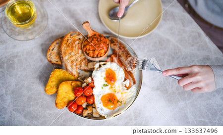 Eating english breakfast menu tea fried eggs baked beans in tomato sauce and grilled bacon sausage 133637496