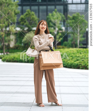Full body adult business asian woman holding coffee cup and shopping bag on black friday sale 133637503