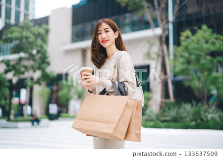 Single beautiful smiling adult business asian woman holding coffee cup and shopping bag Single beautiful smiling adult business asian woman holding coffee cup and shopping bag 133637509
