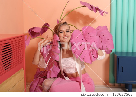 Cheerful woman posing amidst vibrant tropical plant leaves 133637563