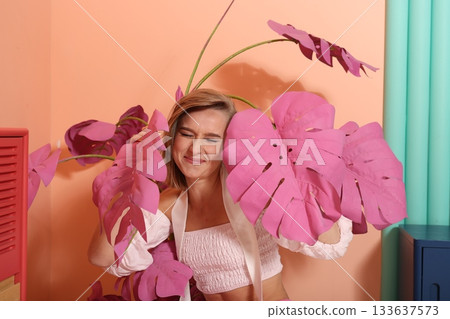 Happy woman with pink leaves and playful bright studio atmosphere 133637573
