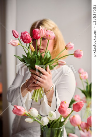 Indoor scene with woman presenting colorful tulips joyfully 133637582