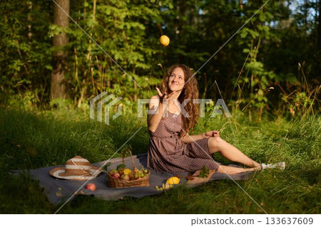 Cheerful young woman balancing lemons in sunny meadow setting Cheerful young woman balancing lemons in sunny meadow setting 133637609