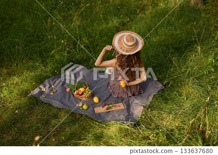 Girl checks fruit, Woman reclining on blanket inspecting orchard produce 133637680