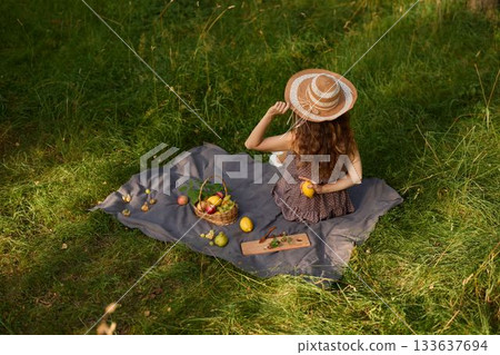 Stylish woman relaxing outdoors amid fresh fruit and warm sun 133637694