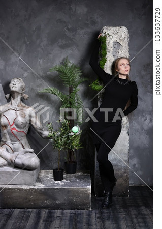 Chic female model poses near classical sculptures and lush ferns 133637729