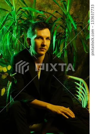 Casual yet sophisticated young man surrounded by vibrant green lights Casual yet sophisticated young man surrounded by vibrant green lights 133637733