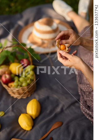 Caucasian woman delights in tasting apricot during outdoor gathering Caucasian woman delights in tasting apricot during outdoor gathering 133637742