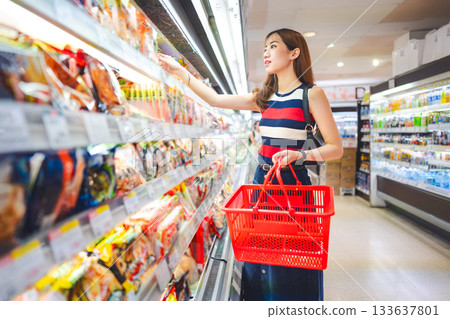 Adult asian woman customer supermarket shopping choosing instant food ready meals at grocery store Adult asian woman customer supermarket shopping choosing instant food ready meals at grocery store 133637801