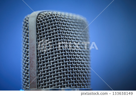 A detailed view of a microphone with a blue backdrop. A detailed view of a microphone with a blue backdrop. 133638149
