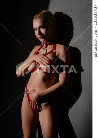 Woman poses confidently in leather belts against a gray studio background 133638437
