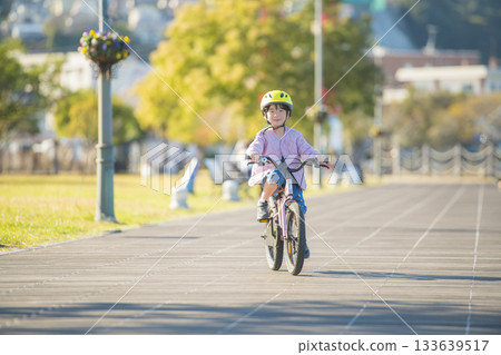 Active cycling of a girl riding a pink bicycle in a Japanese park Active cycling of a girl riding a pink bicycle in a Japanese park 133639517