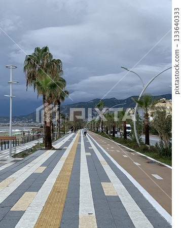 seaside walkway reflection, overcast seafront with puddles reflecting moody sky seaside walkway reflection, overcast seafront with puddles reflecting moody sky 133640333