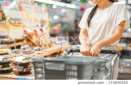 Young adult asian woman consumer choosing ready meals cooked food at supermarket store choice buying 133640350