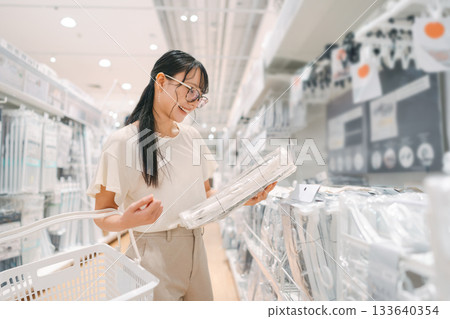 Happy smiling asian woman with shopping basket choosing product for home japan furniture Happy smiling asian woman with shopping basket choosing product for home japan furniture 133640354