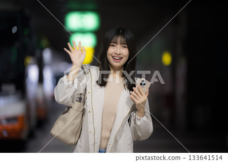 Women's commute to work and home scenes looking at their smartphones at city stations, airports, and bus terminals at night, and urban lifestyles. Bye-bye 133641514