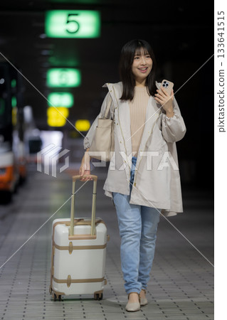 女性通勤上下班的場景,她們在夜間的城市車站、機場和汽車站低頭看手機,展現了都市生活方式。全身照 女性通勤上下班的場景,她們在夜間的城市車站、機場和汽車站低頭看手機,展現了都市生活方式。全身照 133641515