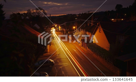 The flickering of car headlights through a quaint village creates a mesmerizing light show adding a touch of magic to its oldworld charm 133641645