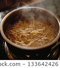 A pot of boiling water with a of uncooked soba noodles inside 133642426