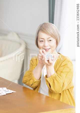 Senior women playing cards in the living room Senior women playing cards in the living room 133642466