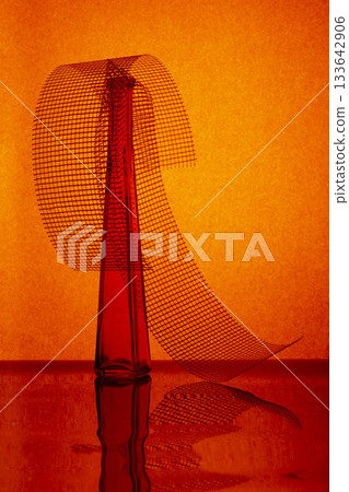 Still life with red glass bottle on a reflective surface 133642906